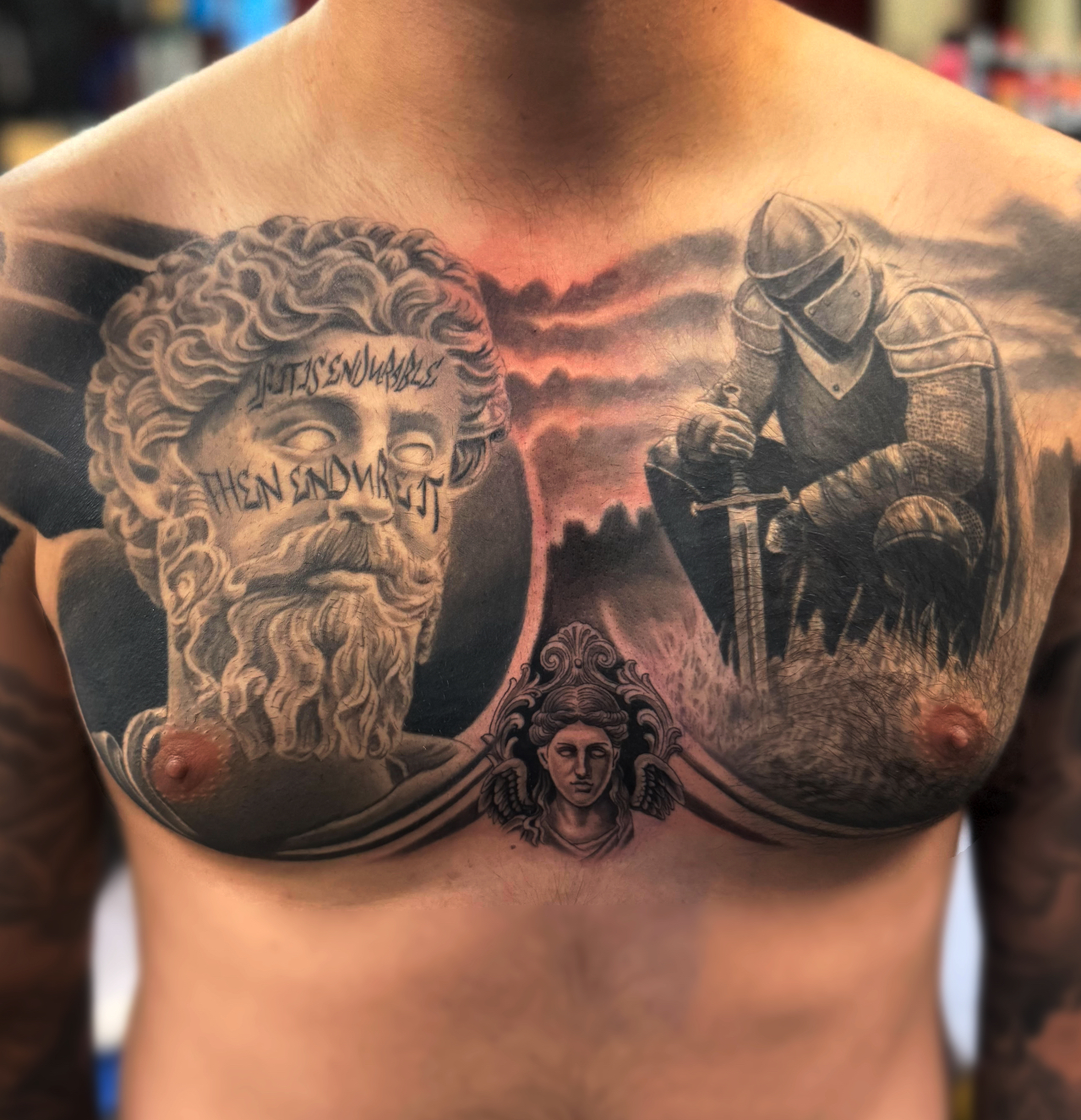 Black and grey realism chest tattoo of a bearded stoic philosopher bust beside an armoured knight resting on a sword