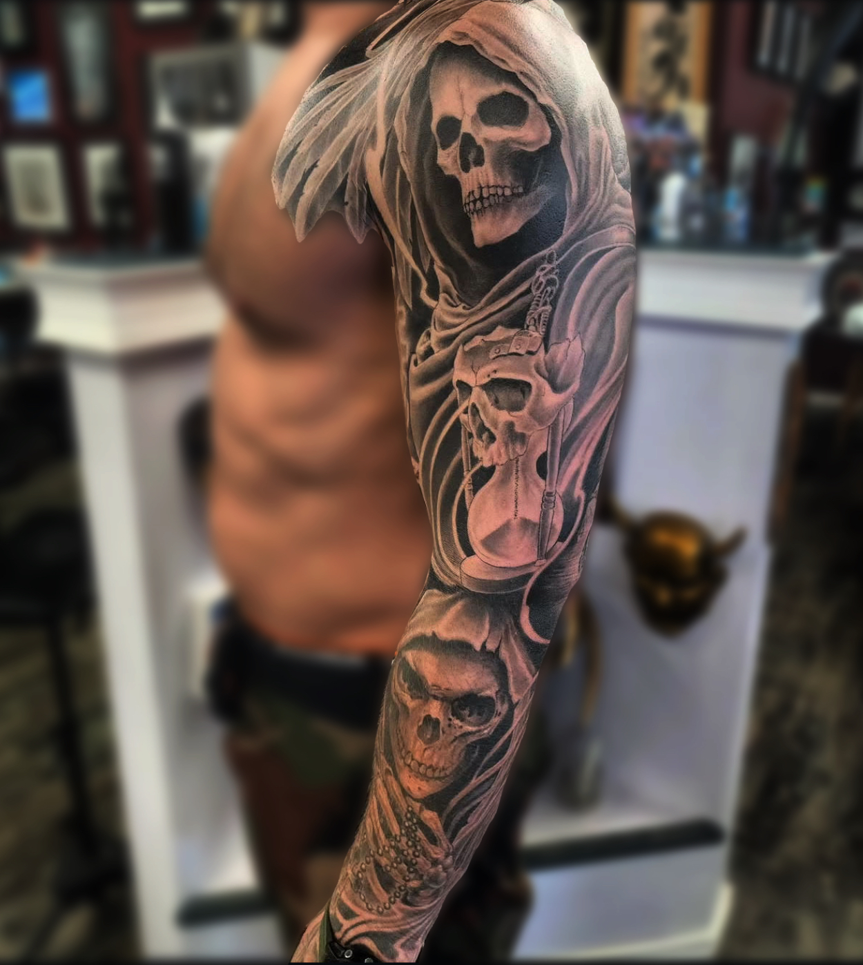 Black and grey realism full sleeve featuring a hooded grim reaper, hourglass, and skulls