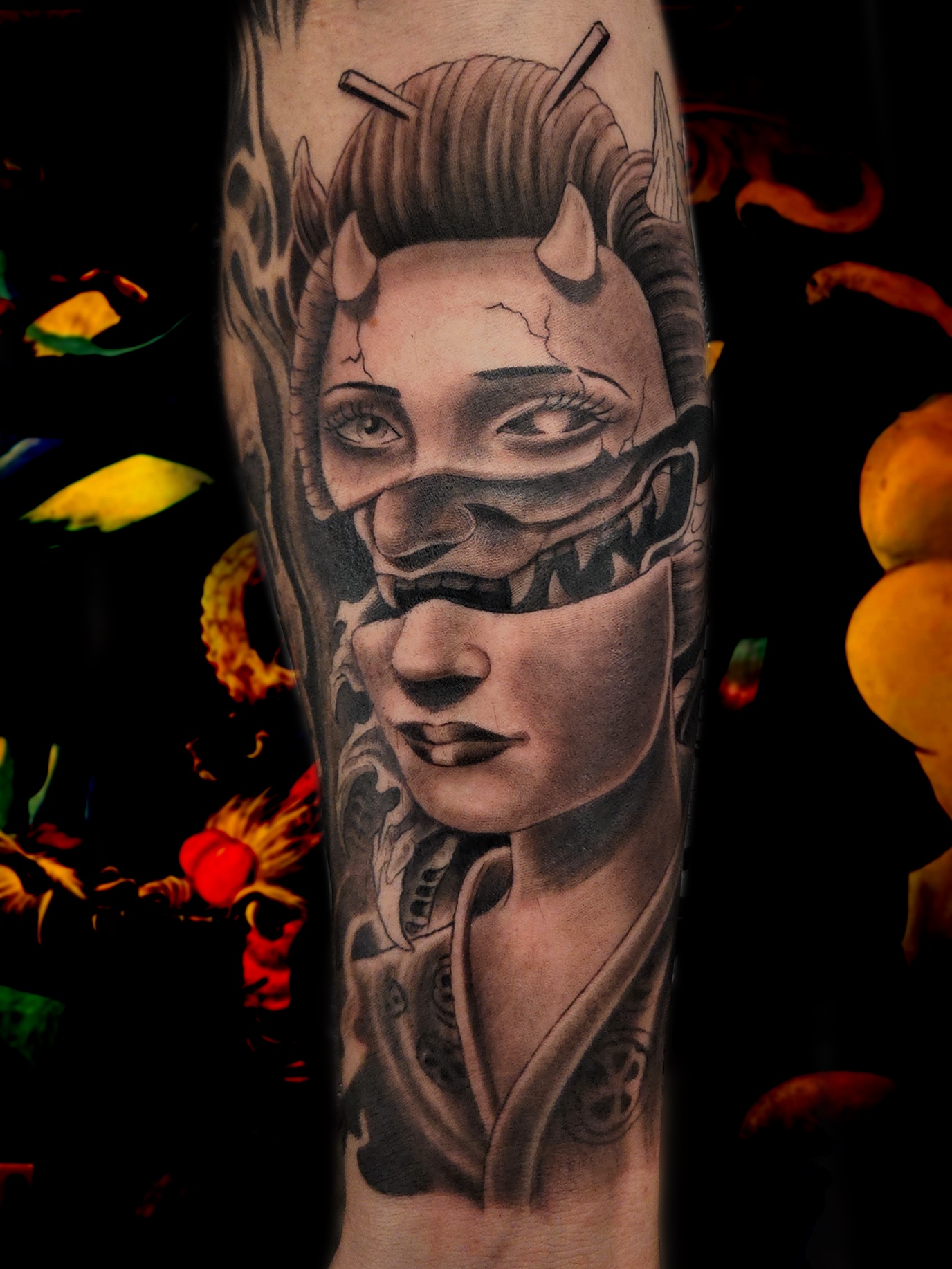 Black and grey realism forearm tattoo of a horned geisha face split into shifted panels