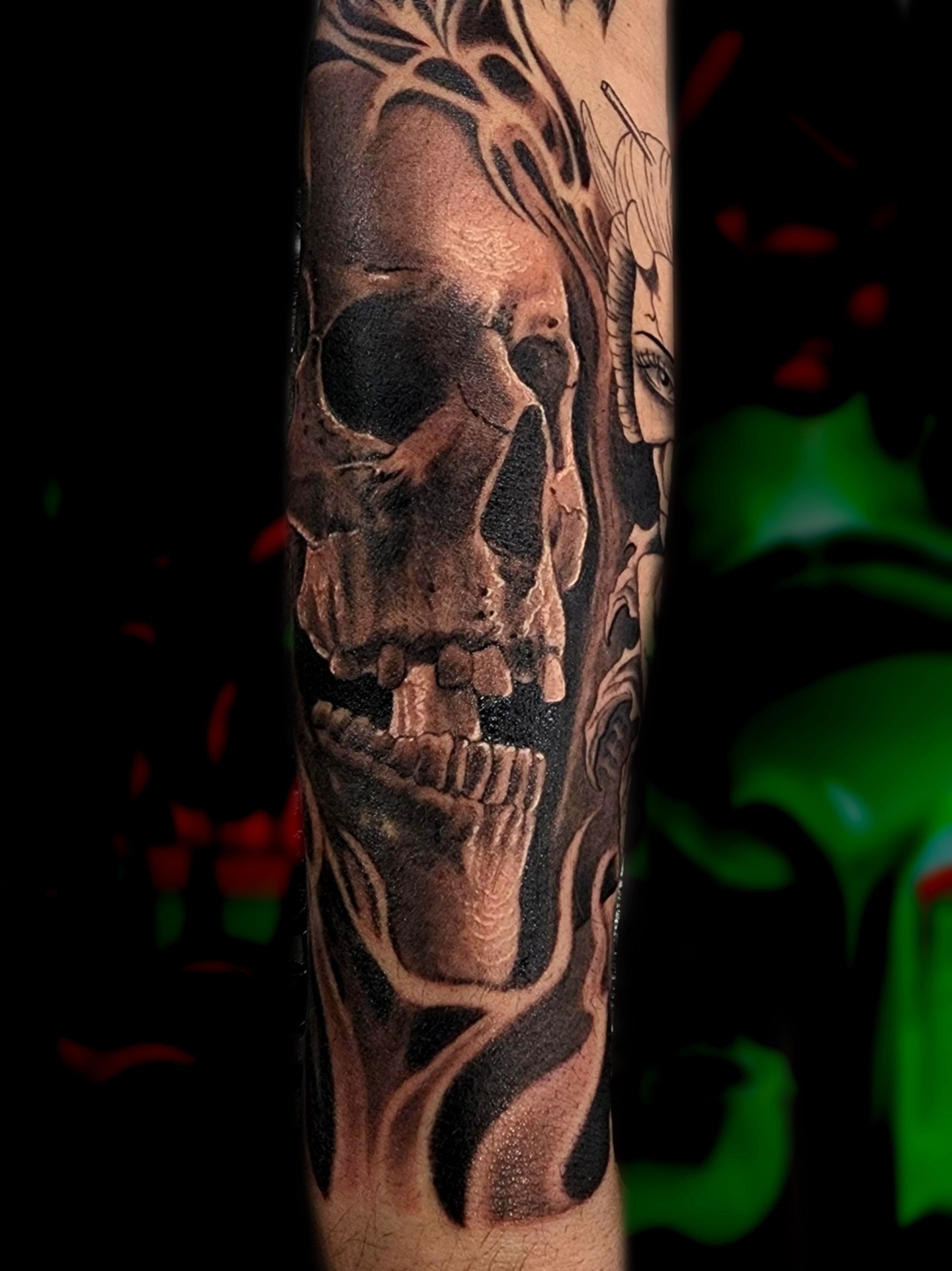 Black and grey realism forearm tattoo of a skull beside a horned oni woman in dark smoke