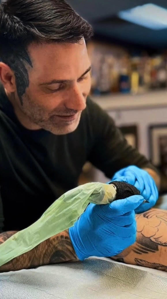 Eric Sabatier tattooing a client's arm in his Edmonton studio