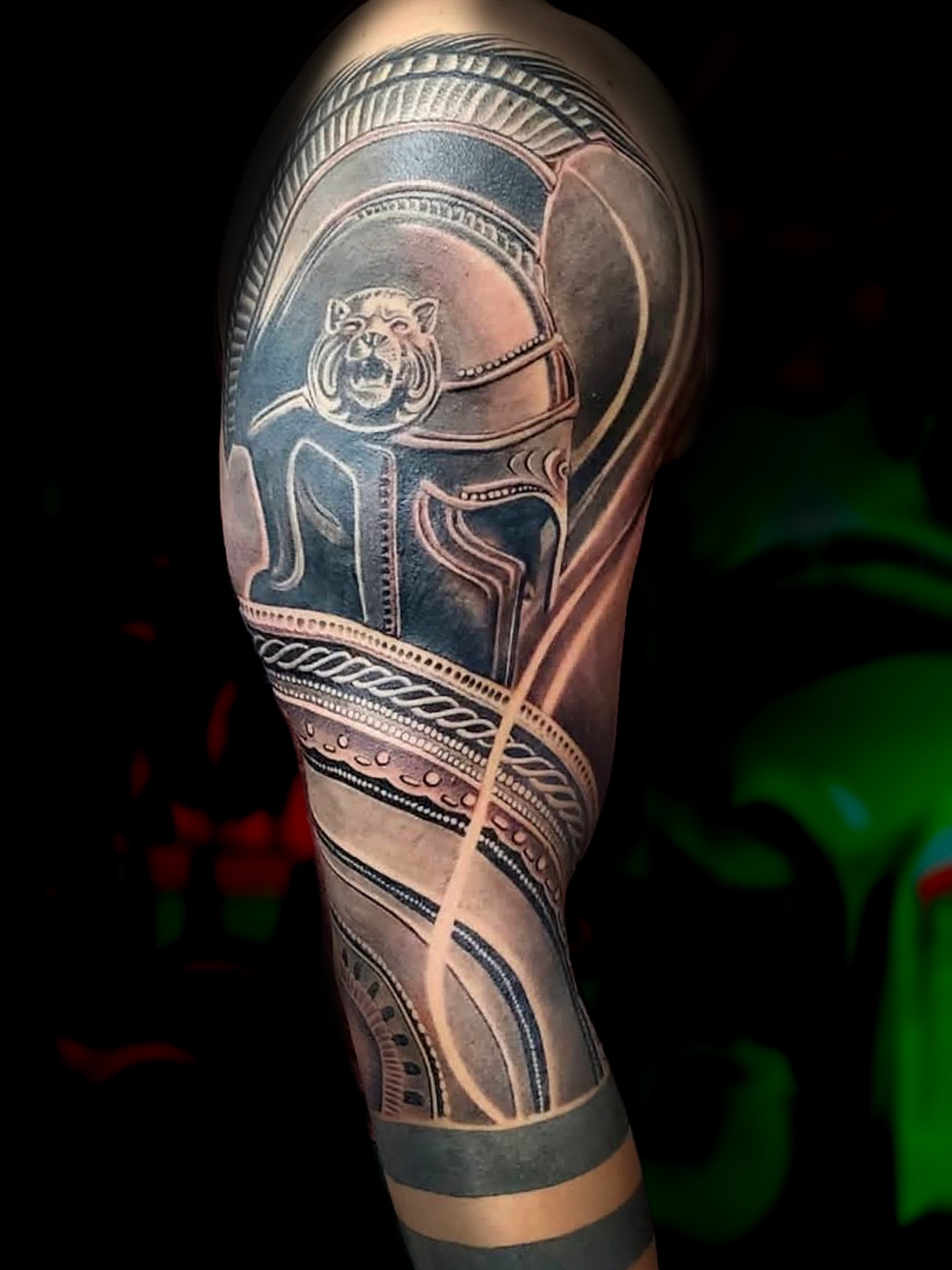 Black and grey realism sleeve of a Roman-style helmet and armour with lion crest relief